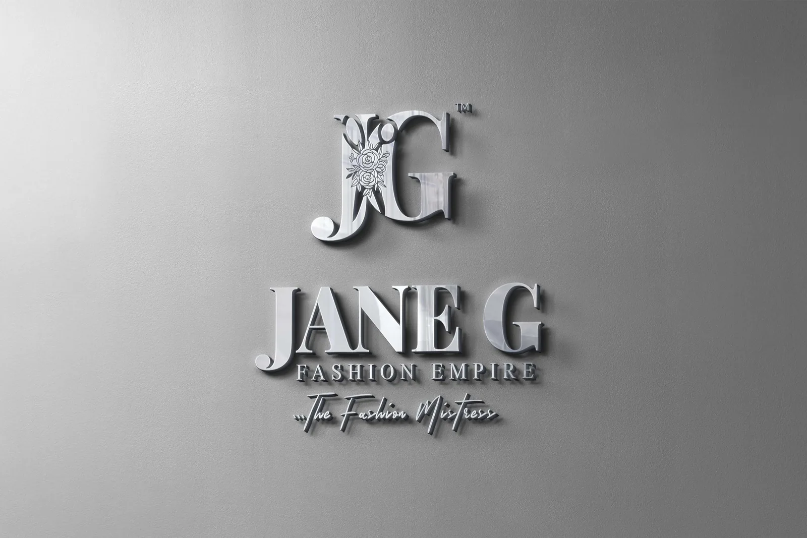 Brushed-silver 3D sign on a grey wall: JG monogram above JANE G Fashion Empire and The Fashion Mistress