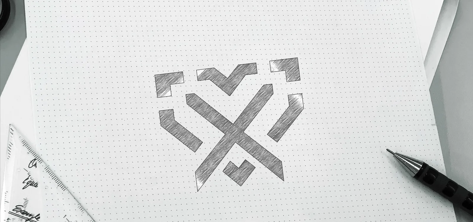Pencil sketch of the Vixus monogram on dotted paper, the V, X and heart built from angled bars